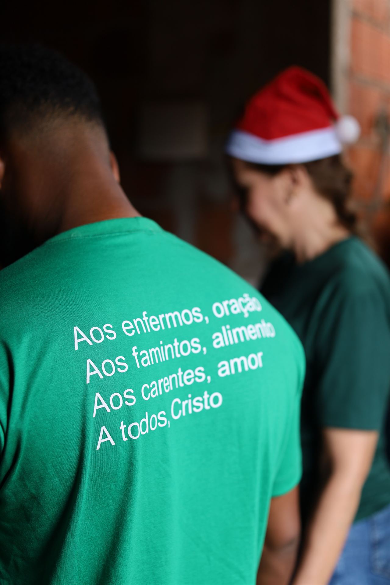 Voluntário de costas vestindo camiseta verde com a missão da ACASE impressa