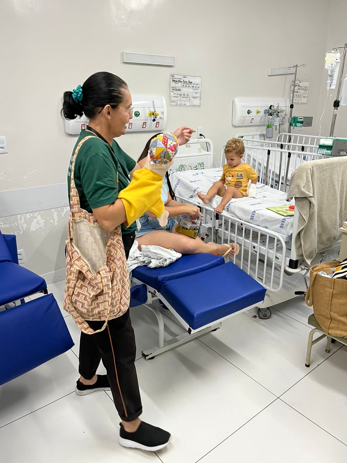 Voluntária da ACASE abraça uma menina sorridente que segura uma boneca